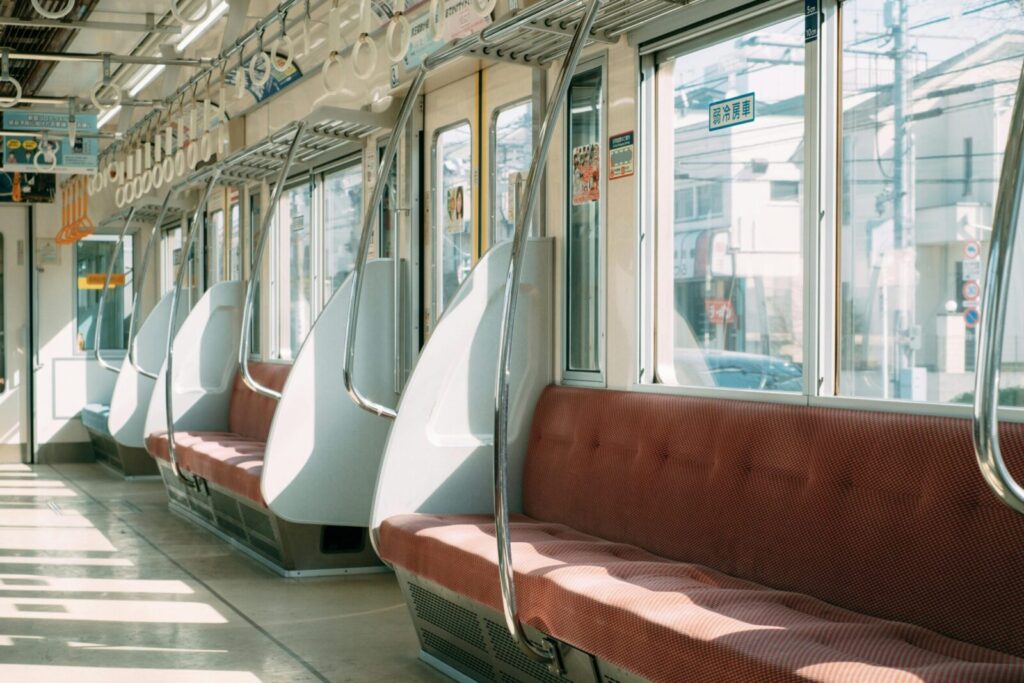 Sunlit empty train interior with red seats and modern design reflecting urban transport.