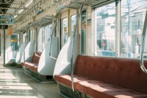 Sunlit empty train interior with red seats and modern design reflecting urban transport.