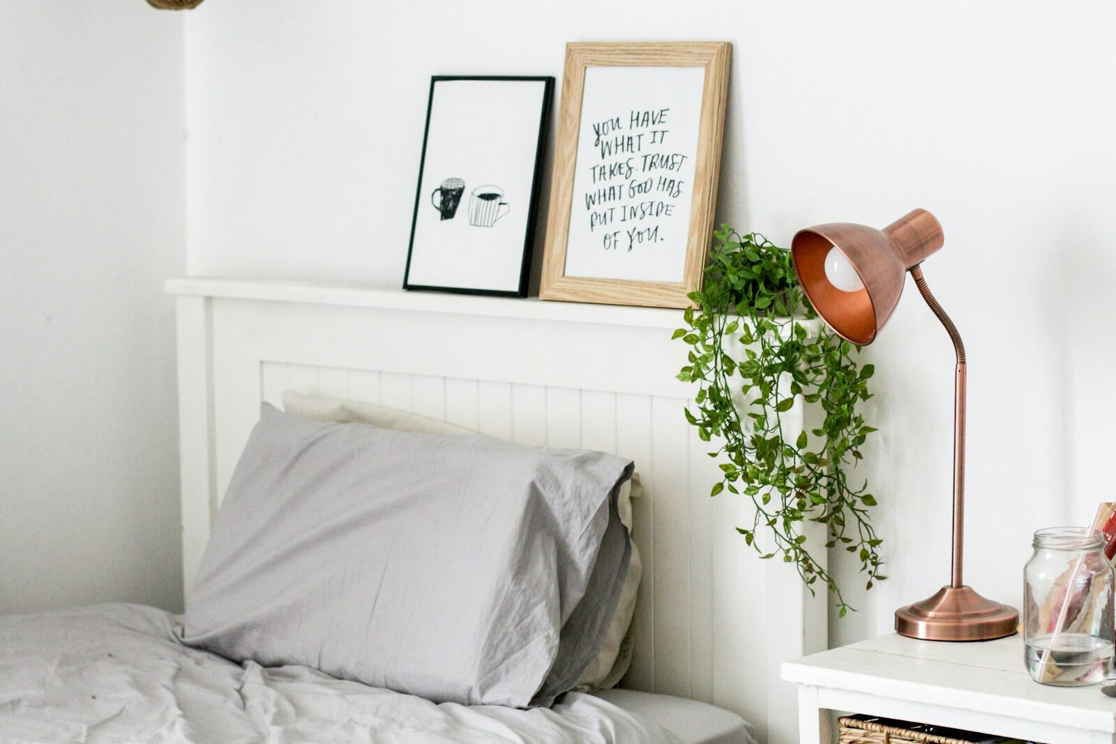 two gray pillow on bed near vine plant and table lamp inside room